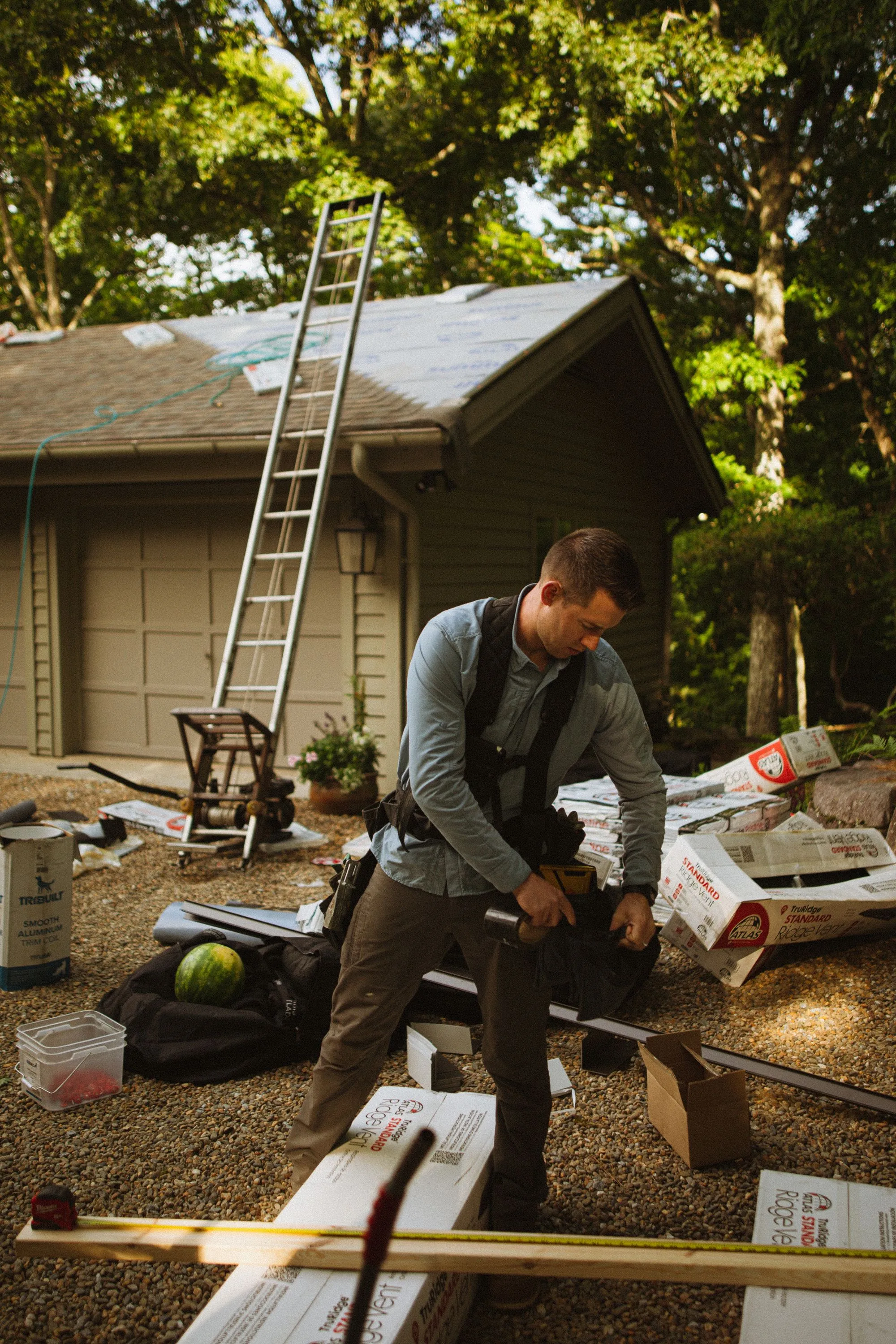 A roofing contractor working beside a ladder at the side of a house