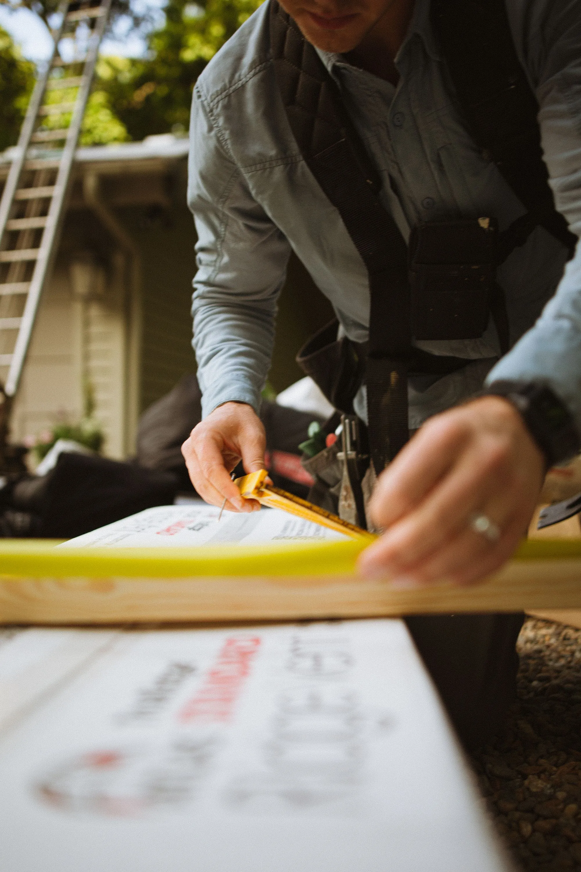 Hands running a tape measure and writing the figure onto a yellow estimate pad