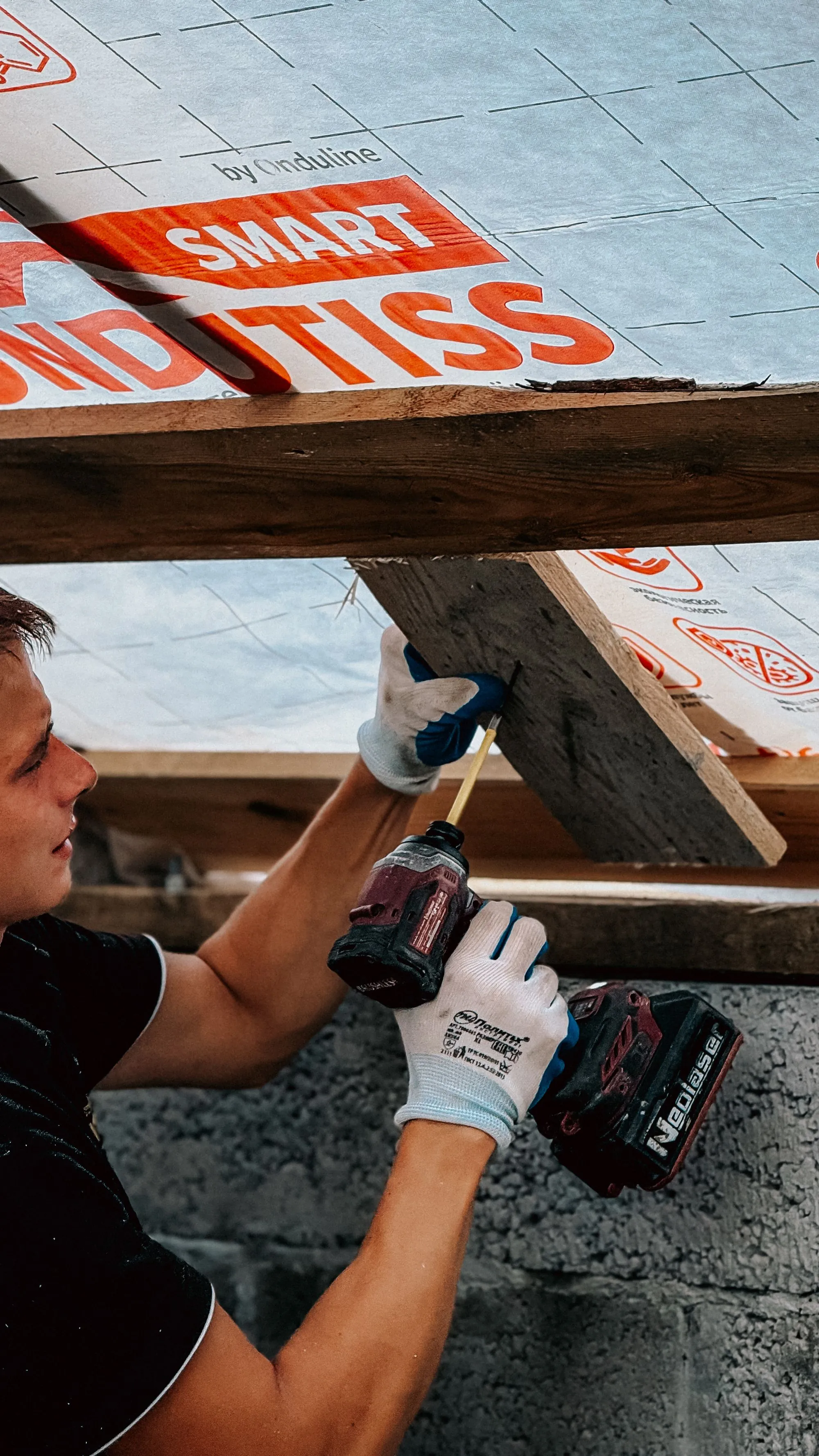 A roofer fastening a new board across a residential roof deck