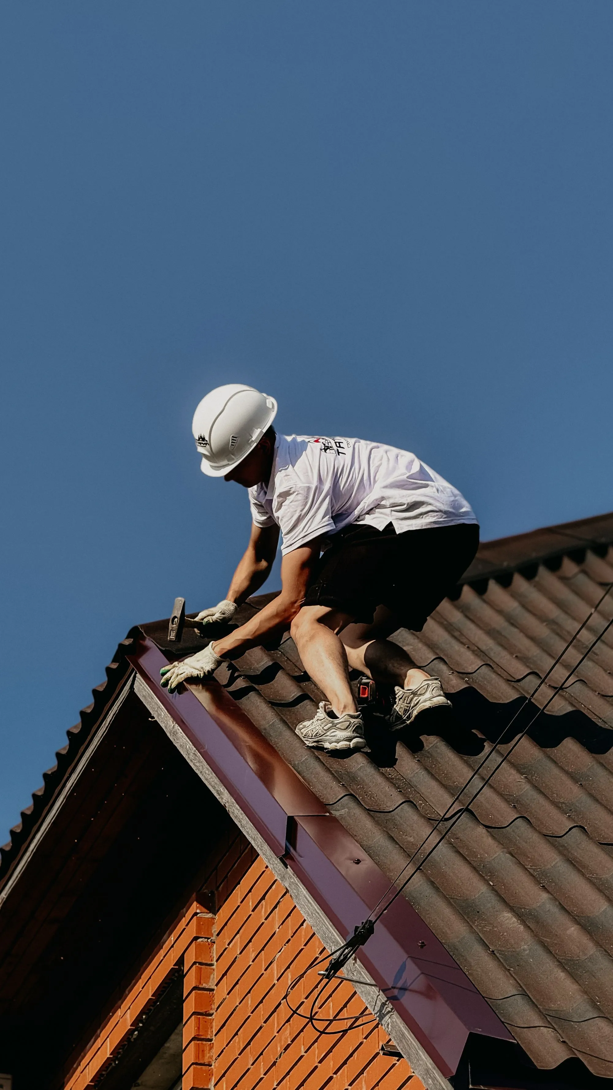 A climbing harness and tool belt set out at the foot of a ladder before a roof inspection