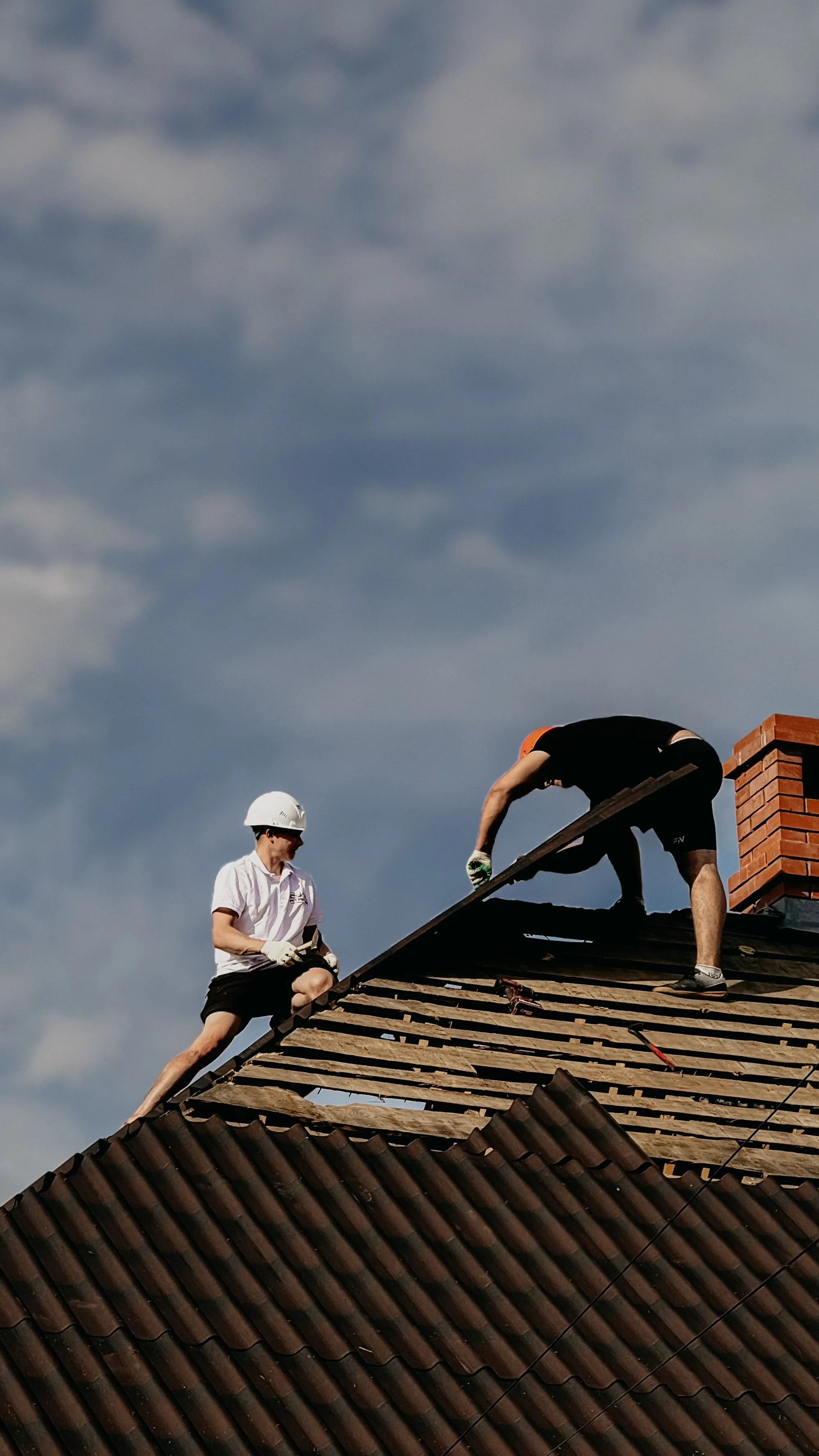 A roofer working on shingle courses at the edge of a residential roof